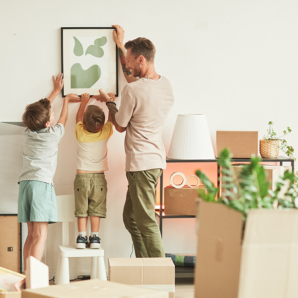 Contact us for a FREE online conveyancing quote. Picture if a father and sons putting up pictures in their new home.