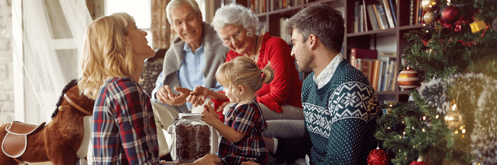 A family at Christmas gathered around the tree exchanging presents.