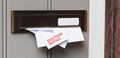 Picture of mail including an eviction notice being posted through a letterbox.