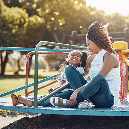 Child Arrangements - Picture of a mother and daughter on a roundabout during the school holidays.