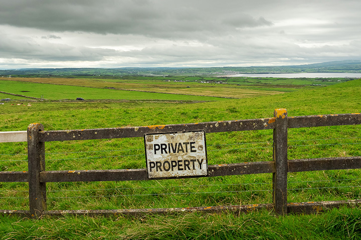What is Adverse Possession? - Picture of a field with a sign fixed to a fence that reads "Private Property"