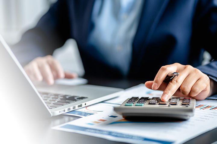 Bridging Finance Explained: More Than Just a Stopgap. Picture of a business person making calculations using a calculator.