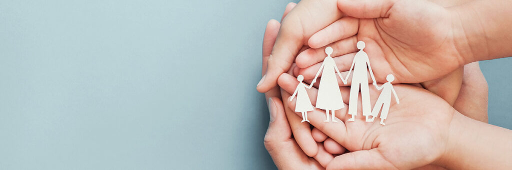 Going on holiday? Make Sure Your Will Is Up to Date. Picture of open hands holding a paper cut out of a family.