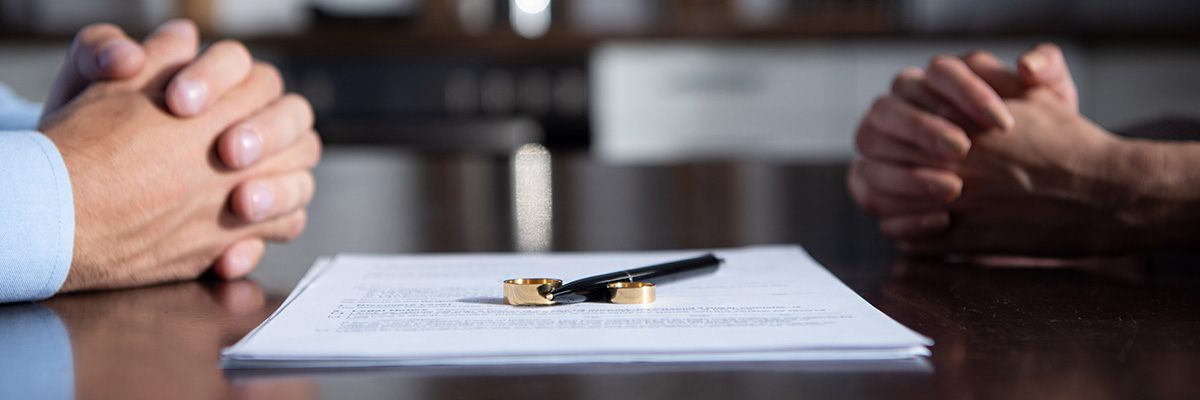 Divorce Week 2025 - Picture of a couple sitting opposite each other at a table with divorce paperwork in between them both.